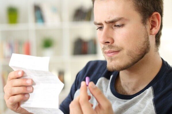 un home estuda o folleto para buscar un antibiótico para a prostatite